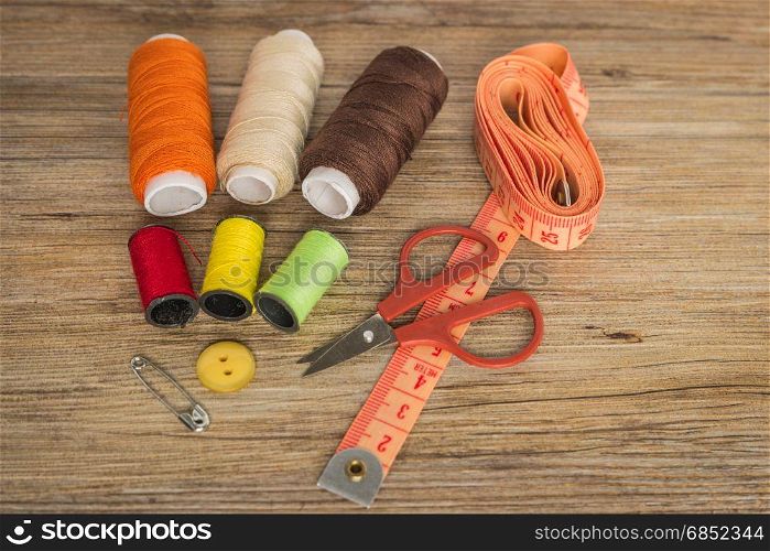 Sewing background. Accessories for needlework on wooden background. Spools of thread, scissors, buttons, measuring tape, sewing supplies. Set for needlework top view with copy space.