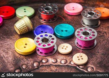 Sewing button set. plastic sewing button and thread coil on a copper retro background