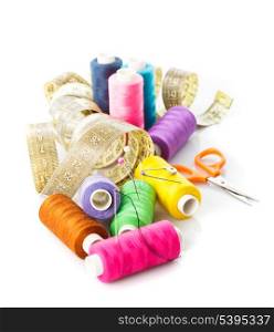 Sewing items: multicoloured threads, pins, meter and scissors on white