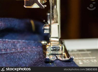 Sewing machine and jeans fabric. Focus on the needle.
