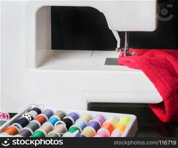 sewing machine and red cloth, sewing process in the phase of overstitching,colored spools.