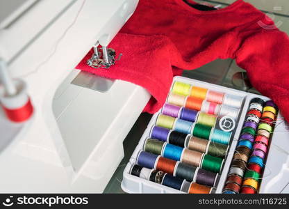 sewing machine and red cloth, sewing process in the phase of overstitching,colored spools.