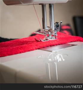 sewing machine close up and red cloth, sewing process in the phase of overstitching