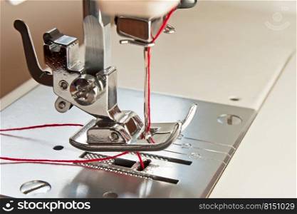 sewing machine presser foot and needle with red thread. sewing machine