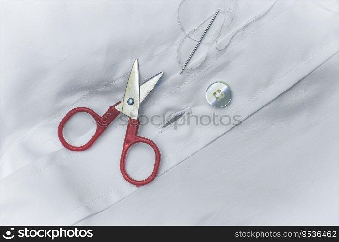 Sewing needle and thread drills to mend a broken button on shirt 