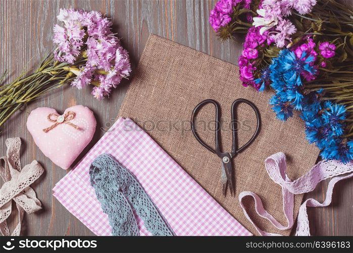 Sewing set of different decorative elements for handicraft and items for handmade on wooden background. Set for needlework pastel colors