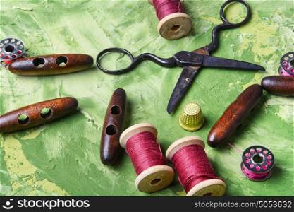 sewing supplies on green background. Sewing kit.Old scissors and wooden buttons on green background