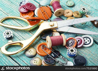 Sewing tools, scissors, buttons and threads on wooden table. Sewing supplies on wooden table