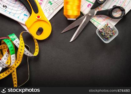 sewing tools thread with scissors and measuring tape on dark