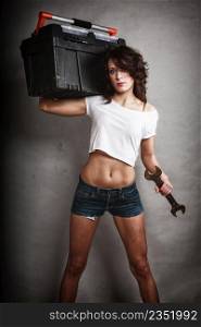 Sex equality and feminism. Sexy girl holding toolbox and wrench spanner on gray. Young attractive woman working as construction worker. Studio shot.