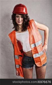 Sex equality and feminism. Sexy girl in safety helmet and orange vest. Attractive woman working as construction worker.
