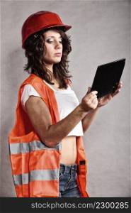 Sex equality and feminism. Sexy girl in workwear safety helmet and orange vest using tablet touchpad. Attractive woman as construction worker. Technology.