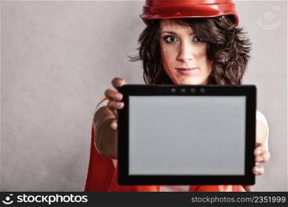 Sex equality and feminism. Sexy girl worker in safety helmet and orange vest showing copy space on tablet touchpad.