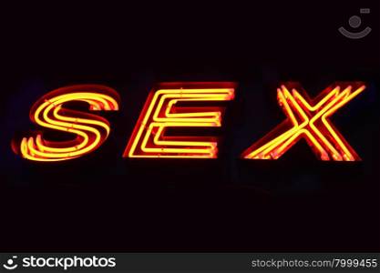 Sex shop neon sign close-up over black background
