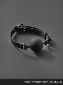 Sexual attribute for erotic games BDSM ball gag with small openings on a black background with soft shadows and copy space. Sex and erotic games concept.. BDSM ball gag with openings.
