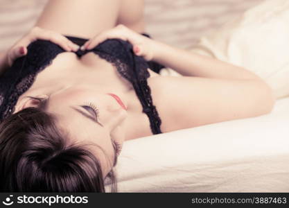 Sexuality and temtation of women. Attractive seductive long curly hair woman in black lingerie on bed. Indoor.