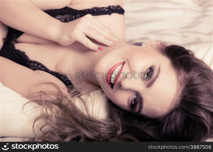 Sexuality and temtation of women. Attractive seductive long curly hair woman in black lingerie on bed. Indoor.
