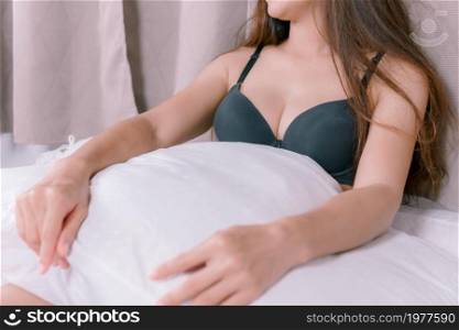 Sexy Asian woman sitting on white bed focus on the chest