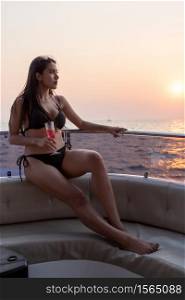 Sexy Asian Women in Bikini with Champagne Glass on her Private Yacht at Sunset.