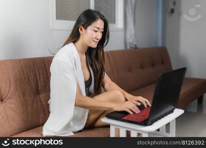 Sexy asian women sitting on the sofa working with a notebook, concept work from home.