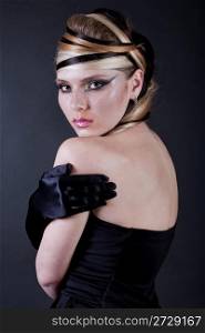 Sexy beautiful makeup artist looking with her black hand glove over black background