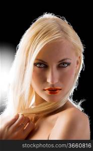 sexy blond girl in a close up portrait on black and strong back light