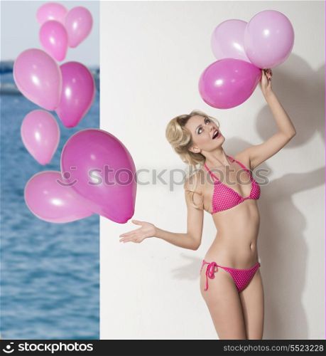 sexy blonde female wearing pink swimwear and playing with balloons. Funny portrait , summertime.