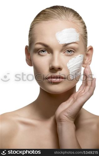 sexy blonde girl applying cream cosmetics treatment on her skin visage with fingers. Looking in camera. Beauty shoot