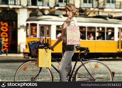 sexy blonde girl going shopping with bicycle, some bags are in the bike basket and she wearing white shirt and jeans