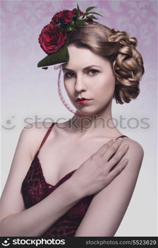 sexy blonde girl with romantic floral hair-style, sexy red dress and heart shaped lipstick. Red roses in the hair