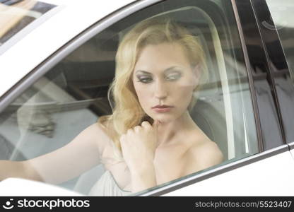 sexy blonde girl with thoughtful expression and elegant style posing in a white car