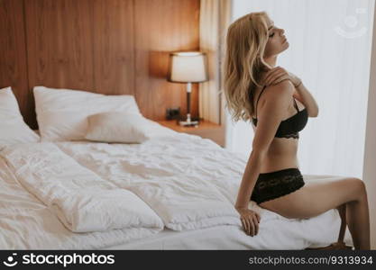 Sexy blonde woman in lingerie sitting on bed