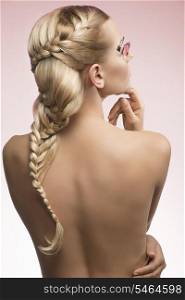 sexy blonde woman with cute long braid hair-style and creative feathered make-up showing her sensual nude back