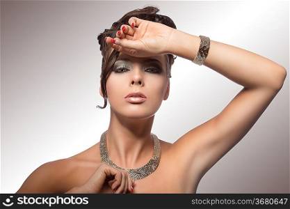 sexy brown woman in fashion pose with curly hairdo, cute make-up, nacked shoulder and jewelery on white background