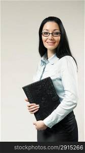 Sexy brunette businesswoman / assistant / secretary portrait. Girl holding leather folder. Wearing shirt, skirt and glasses. One of a series.