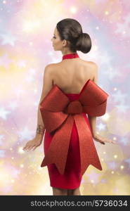 sexy brunette girl with elegant christmas style posing turned on her back with elegant red dress with big glitter bow, naked shoulders and golden jewellery