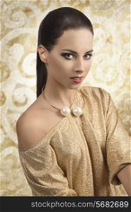 sexy brunette girl with golden evening dress and naked shoulder, posing with trendy necklace and stylish make-up, long smooth hair, sensual eyes