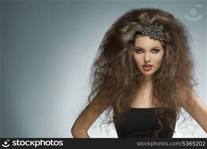 sexy brunette girl with long curly voluminous hair-style and glitter accessory in the hair posing in fashion portrait with cute make-up