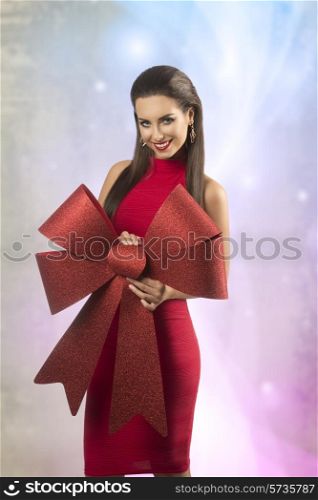 sexy brunette woman in christmas portrait posing with red dress and big red bow, smiling and looking in camera