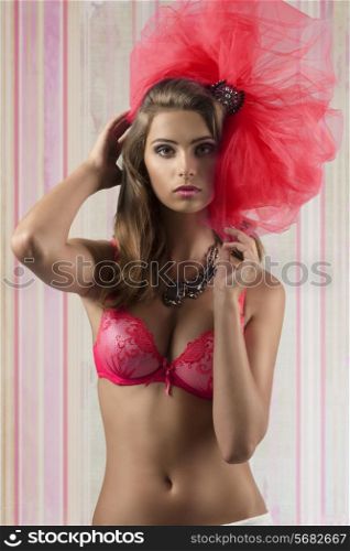 sexy brunette woman posing with red bra and big tulle accessory on the head, looking in camera