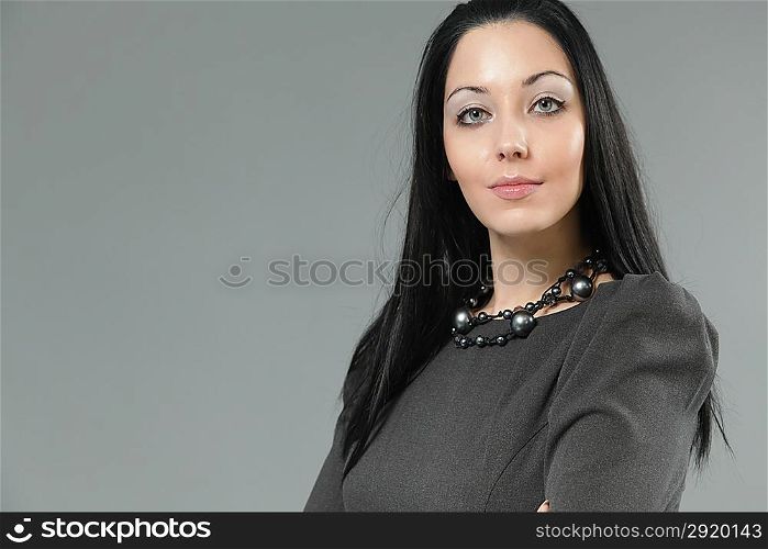 Sexy brunette woman with passionate lips wearing grey dress. Studio portrait.