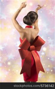 sexy christmas woman with elegant glamour red dress and big bow posing turned on her naked back with golden jewellery