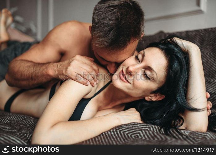 Sexy couple makes love in bed, erotica. Erotic scene in bedroom, sexual relationship of man and woman. Sexy couple makes love in bed, erotica