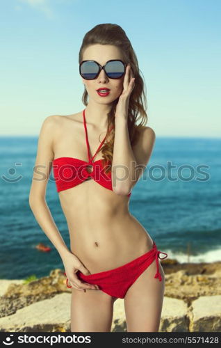 sexy fit female in holiday time posing with red swimwear, sunglasses and natural hair-style.