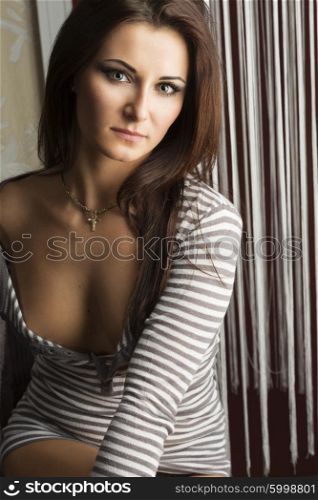 sexy girl brunette , in a indoor portrait , in natiral light , she has a open t-shirt on her breast . looking in camera