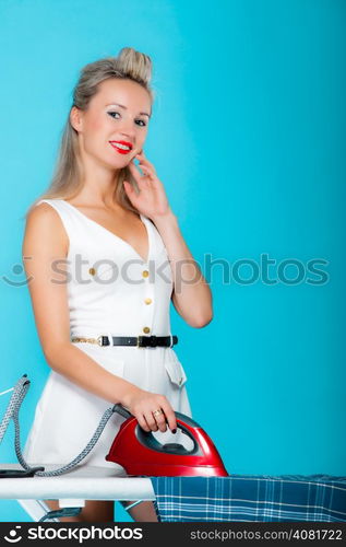 Sexy girl retro style ironing male shirt, woman housewife in domestic role. Traditional sharing household chores. Pin up housework. Vivid blue background