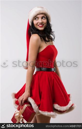 Sexy girl wearing Santa Claus clothes - dress and hat standing with Christmas gifts