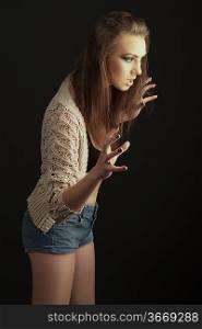 sexy girl with open sweater and shorts jeans, she is turned of three quarters at left in aggressive pose