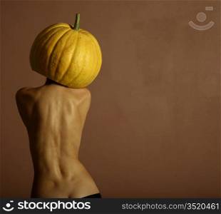 Sexy lady with big pumpkin on head. Surrealstic portrait.