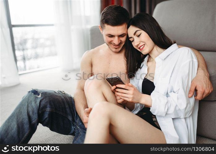 Sexy love couple hugging and look photo on the phone. Intimate life, sex lovers relationship. Love couple hugging and look photo on the phone